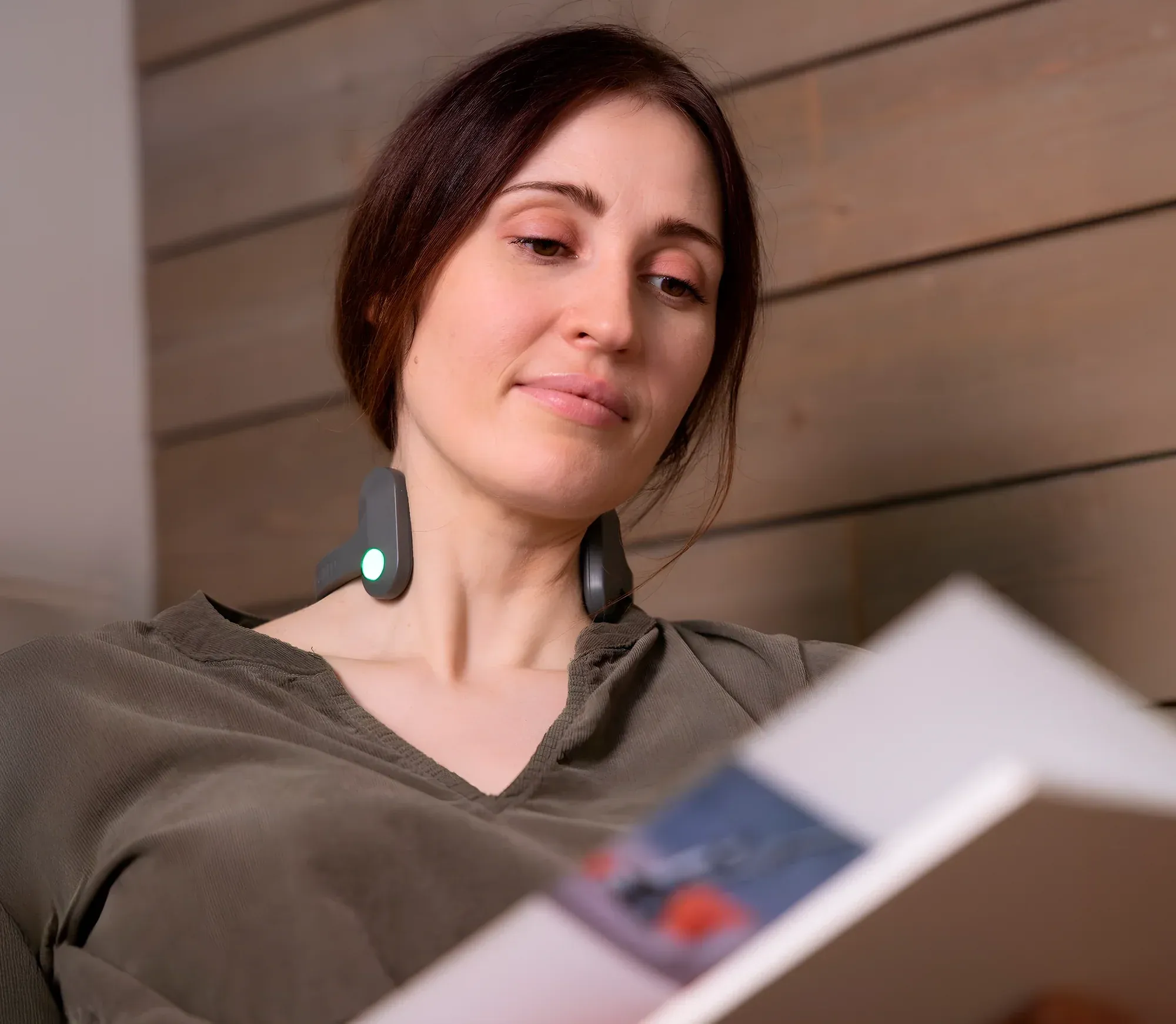 Woman relaxing at home while wearing the Pulsetto FIT device